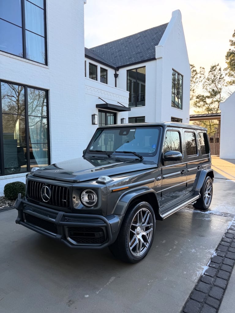 Black Mercedes-Benz G-Class SUV parked in front of modern white house with black roof